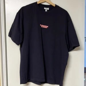 Mörkblå t-shirt med tryck - Mörkblå t-shirt med färgglatt tryck på baksidan som föreställer en pool och palmer. Texten 'Swimming in SoCal' finns både fram och bak. Perfekt för en avslappnad stil.