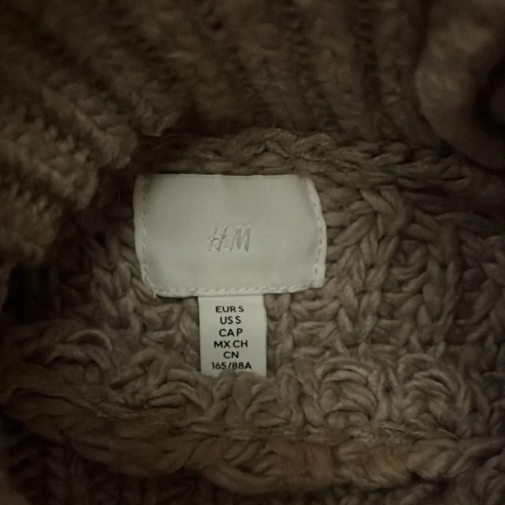 Säljer en snygg beige stickad tröja från H&M. Tröjan är croppad med långa ärmar och har en ribbad design som ger en trendig look. Perfekt för kyligare dagar!. Neuletakit & Villapaidat.