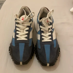 New Balance XC-72 sneakers - Snygga New Balance XC-72 sneakers i blått och vitt.. Skorna har en unik design med grov sula och klassisk snörning. Perfekta för en sportig look. Box och ett par andra snören finns också.