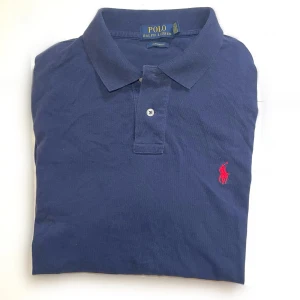 Ralph Lauren | Pike - Ralph Lauren Piké | Stl M | Den klassiska marinblå + röd kombinationen | Ett plagg man måste ha i sin rotation! Fungerar till allt!| Nypris 1299