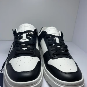 Svartvita sneakers från Tommy Jeans - Snygga svartvita sneakers från Tommy Jeans med klassisk design. Skorna har snörning och en robust sula som ger bra komfort. Perfekta för en stilren look.