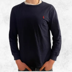 Mörkblå långärmad tröja från Ralph Lauren - Säljer en stilren mörkblå långärmad tröja från Ralph Lauren med det klassiska röda logotypen på bröstet. Perfekt för en avslappnad och snygg look. Den är i endast användt ett fåtal gånger och har inga defekter eller likande. Den är storlek L i barnstorlek vilket är ungefär som en S. Personen på bilden är 176 centimeter. Vid några frågor eller funderingar är det bara att höra av sig.