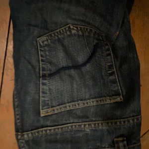 Blå jeansbyxor - Säljer ett par klassiska blå jeansbyxor med femficksdesign. Låg midja och dom är lagom utsvängda. Säljer dom för att dom är för stora! Jätte fint skick.