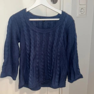 Blå stickad tröja - Säljer en mysig blå stickad tröja med flätmönster. Tröjan har trekvartsärmar och utsvängd i harmar och nertill.