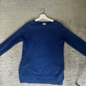 Blå stickad tröja från Vila - Säljer en snygg blå stickad tröja från Vila. Tröjan har en klassisk design med långa ärmar och ribbade kanter vid ärmslut och nederkant. Perfekt för kyligare dagar. Passar bra till både jeans och kjol. Bakdelen är några centimeter längre💙