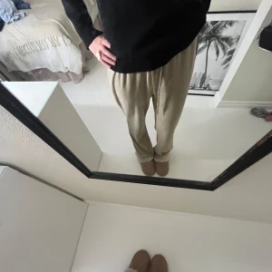 Beige mjukisbyxor från Gina Tricot - Säljer ett par bekväma beige mjukisbyxor från Gina Tricot. Byxorna har en loose passform och är perfekta för en avslappnad stil. De har elastisk midja och muddar vid bensluten för extra komfort.