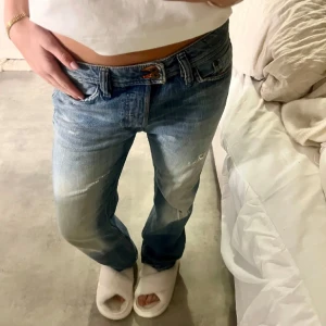 Diesel lågmidjade jeans  - Säljer ett par blå jeans med slitningar och en avslappnad passform. De har en låg midja och klassisk femficksdesign. Perfekta för en casual look.