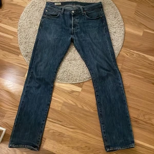 Blåa Levi’s 501 - Säljer mina blå Levi’s femhundraettor då de är lite väl tighta i min midja. Förutom ett litet rött märke   på vänster ficka (bild 4) och lite goa slitningar i hälarna så är de i mycket bra skick och lyfter vilken outfit som helst!
