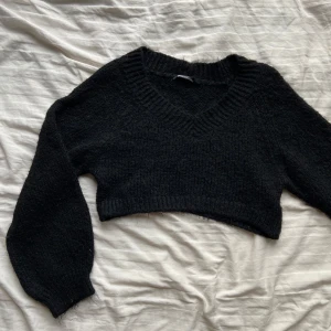 Svart stickad croppad tröja från Gina Tricot - Säljer en svart stickad tröja från Gina Tricot. Den är croppad med en v-ringad hals och långa ärmar. Perfekt för en stilren look. Passar bra till både jeans och kjol.