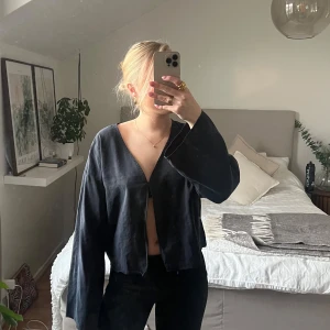 Mörkblå långärmad blus - Snygg mörkblå blus med långa ärmar och en stilren design. Perfekt för en elegant look. Blusen har en enkel knäppning framtill och är tillverkad i ett lätt material.