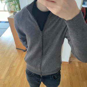 Massimo Dutti Full Zip Cardigan  - Säljer en sjukt fet Full Zip Cardigan från Massimo Dutti. Tröjan är i en mörk grå färg som passar till allt och är i ett tjockare och väldigt skönt material. Den sitter i storlek M och är i ett Bra men använt skick. Hör gärna av er vid frågor eller funderingar!!