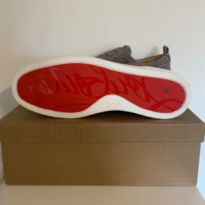 Grå sneakers från Christian Louboutin - Helt nya skor  från Christian Louboutin med den ikoniska röda sulan. Kvitto fås med storlek 42 passar 42-43 skriv om ni har frågor möts endast upp vid Täby eller Stockholm vid snabb affär kan jag gå ner i pris