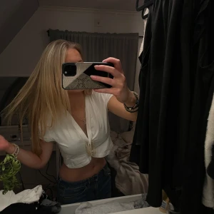 Vit knytblus - Säljer en stilren vit blus med krok framtill så behövs ej klämma framtill. Blusen har en rundad design och korta ärmar, perfekt för en chic look. Den är tillverkad i ett mjukt material som ger en bekväm passform. 