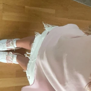 Vita jeansshorts med slitningar - Säljer ett par vita jeansshorts med coola slitningar och fransiga kanter. Perfekta för en avslappnad sommarlook. De har en dragkedja och knapp framtill.💕