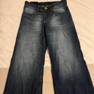 Mörkblå jeansbyxor med vida ben - Snygga mörkblå jeansbyxor med en klassisk femficksdesign och vida ben. De har en knapp och dragkedja framtill. Perfekta för en avslappnad stil. Köpta från WEEKDAY!! 