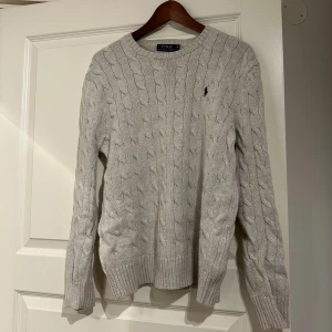 Stickad tröja Ralph Lauren - Stilren grå kabelstickad tröja från Polo Ralph Lauren. Tröjan är i storlek M och i fint skick då den inte är mycket använd.