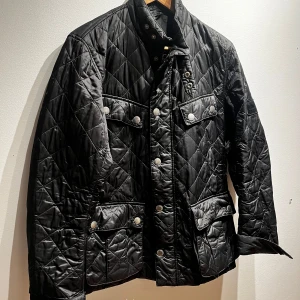 Svart quiltad jacka från Barbour - Säljer en stilren svart quiltad jacka från Barbour. Jackan är i nyskick och är perfekt till våren, Skriv vid minsta lilla