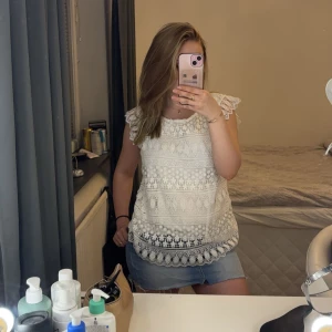 Vit spetsblus från Stradivarius - Säljer en söt vit spetsblus från Stradivarius. Blusen har ett vackert spetsmönster och korta ärmar med volangdetaljer. Perfekt för en sommardag💞På lappen står det stl L men sitter mycket mer som en S!!