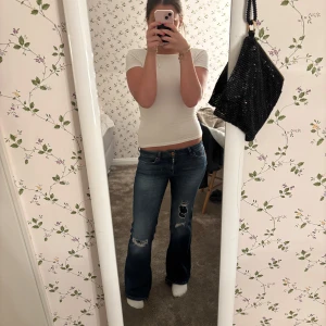 Blå bootcut jeans från ONLY - Snygga blå bootcut jeans från ONLY med slitna detaljer på knäna. De har en klassisk femficksdesign och knappar i midjan. Perfekta för en avslappnad stil. priset kan diskuteras 