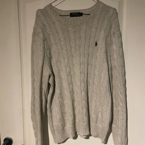 Grå stickad tröja från Polo Ralph Lauren - Säljer en stilren grå stickad tröja från Polo Ralph Lauren med kabelstickat mönster. 