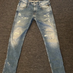 Replay jeans med slitningar  - Snygga blå jeans från Replay i modellen Anbass. De har en distressed look med slitningar och en slim passform. Perfekta för en avslappnad stil. Tillverkade i ekologisk bomull för extra komfort. Minimal defekt som förmodligen går bort i tvätten bild 5