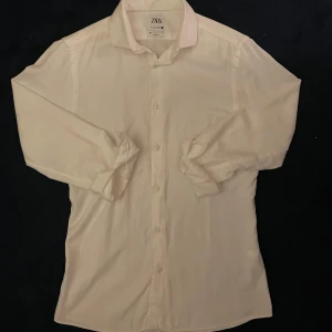 Zara slim fit skjorta  - Säljer en stilren vit skjorta från Zara i slim fit. Den är storlek S och slim fit, säljer då den sitter tight på mig som är 180cm. Skjortan har långa ärmar och har väldigt unik textur. Tveka inte att ställa frågor!