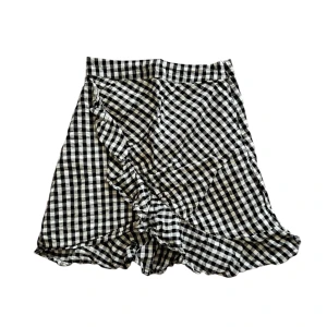 Svartvit rutig kjol med volang - Svartvit rutig kjol med volangdetaljer. Perfekt för att skapa en trendig look.