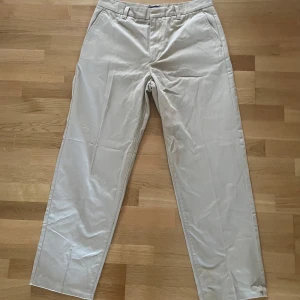 Beige chinos från GANT - Snygga beige chinos från GANT i klassisk stil. De har en rak passform och är tillverkade i ett bekvämt bomullsmaterial. Perfekta för en stilren look.
