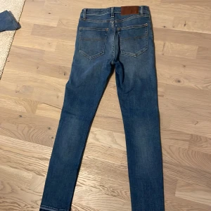 Blå jeans från Tiger of Sweden, 27/30 - Snygga blå jeans från Tiger of Sweden med en klassisk femficksdesign. Size 27/30. Jeansen har en tight passform och är tillverkade i denim med en lätt tvättad look. Perfekta för en stilren vardagslook.