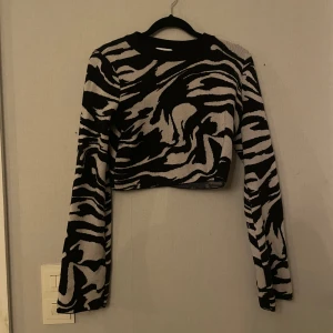 Svart och grå croppad tröja från H&M - Säljer en  croppad tröja från H&M med zebra mönster.