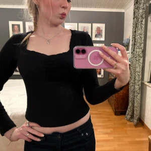 Svart ribbad topp - Snygg svart ribbad topp med lång ärm och en croppad passform. Tröjan har svarta spets detaljer i kragen och en gullig hjärturringning! Passar perfekt till sommaren ☀️