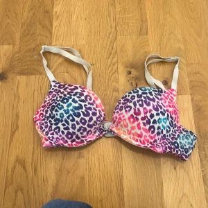 Färgglad leopardmönstrad BH från PINK - Säljer en superfin BH från Victorias secret PINK med leopardmönster i rosa, lila och blå nyanser. Den har justerbara axelband och en bekväm passform. Har lite push, banden går att ta av. Använd Max 8 gånger. 