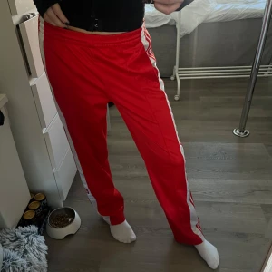 Adidas byxor - Röda coola byxor från adidas i träningsmaterial Storlek S (jag på bilden är 172 och de sitter perfekt) Några små fläckar på de vita ränderna (se sista bild) men inga stora fläckar eller hål som syns Nypris ligger på 829, sänkt priset pga av fläckar