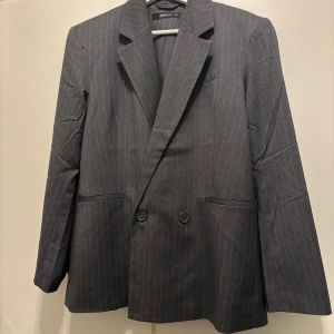 Grå Kritstrecksrandig kavaj  - Supersnygg kavaj från ginatricot, med axelvaddar och oversized, skulle säkert passa som xs och s också. aldrig använd