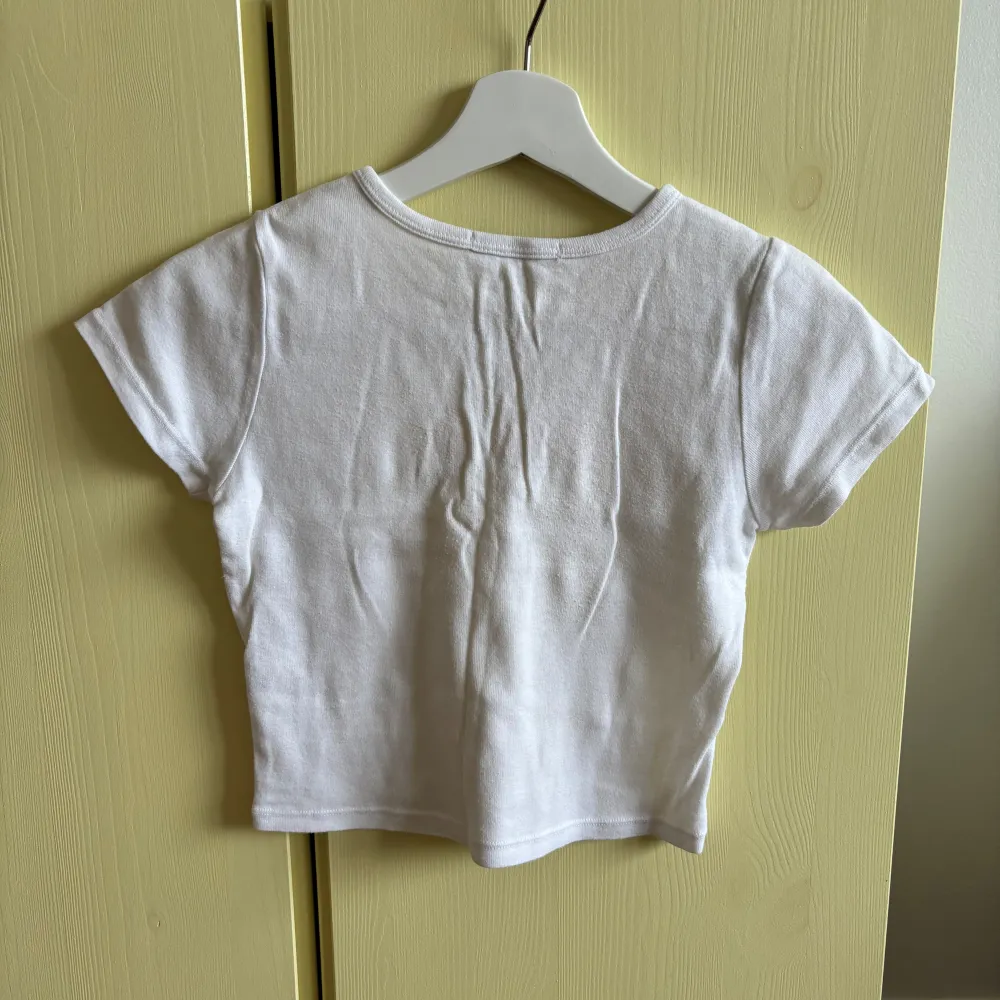 Vit crop top från Brandy Melville🌼  Storlekslapp saknas (one size) men uppskattar storleken till XS.  Material 100% bomull.  Har fått gula fläckar omkring halskanten och armhålor - se bilder.. Toppar.