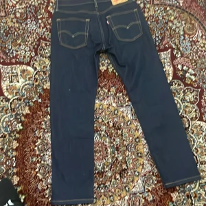 Mörkblå jeansbyxor från Levi's - Snygga mörkblå jeansbyxor från Levi's med klassisk femficksdesign och kontrastsömmar. Perfekta för en stilren look. Använda 1 gång sen köp straight i bena och 30/30 i storlek 