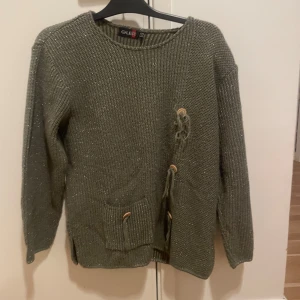  Grön tjock tröja  - En grön tjock tröja med glitter och knappar på