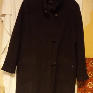 Svart kappa från KappAhl - Säljer en stilren svart kappa från KappAhl i storlek XL. Den är tillverkad av 70% ull och 25% polyester, vilket gör den både varm och hållbar. Kappan har långa ärmar och stängs med knappar framtill. Perfekt för kyligare dagar.
