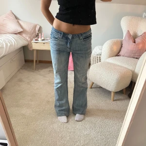 Blå jeans från H.I.S - Säljer ett par klassiska blå jeans från H.I.S med bootcut-stil. De har en normal passform och är lågmidjade och är perfekta för en avslappnad look. Jeansen har en knapp och dragkedja framtill.