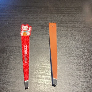 Färgglada pincetter med motiv - Två unika pincetter med roliga motiv, sparsamt användna. Den ena har en röd design med en lyckokatt och texten 'Happiness', medan den andra har ett brunt björnmotiv. Saniteras och tvättas noga innan jag skickar, 15kr/st eller båda för 20kr exklusive frakt!! Kan posta utan spårbart för 22!! 