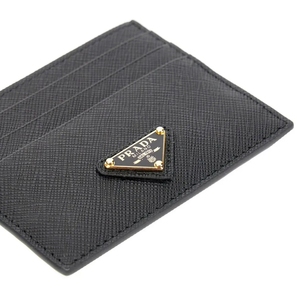 Elegant svart kortfodral från Prada i skinn med plats för flera kort. Den har en stilren design med Pradas ikoniska logotyp i guld på framsidan. Perfekt för att hålla dina kort organiserade med stil. Helt ny med box ny pris 4000kr. Laukut & Käsilaukut.