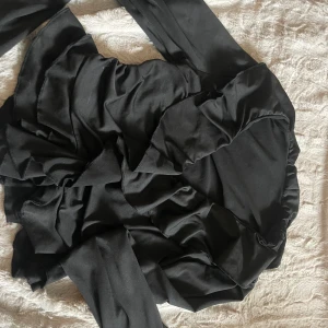 Svart långärmad tröja  - Elegant svart tröja med långa ärmar och volangdetaljer. Perfekt för en stilren look. Tillverkad i ett mjukt och följsamt material som ger en bekväm passform.