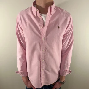 Rosa Ralph Lauren skjorta - Nu säljer vi ännu en fet polo skjorta som passar till alla tillställningar! Skjortan går in en del vid midjan vilken syns på andra bilden. skjortan är i mycket bra skick! Du ska kunna uttrycka stil utan att det kostar för mycket!🕺🍾💼🤩  Storlek👔: sitter som L (fast det står XL) Nypris💰:  ca 1499kr