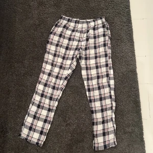 Pyjamasbyxa  - Säljer ett par bekväma rutiga pyjamasbyxor från H&M i storlek S. Byxorna har ett klassiskt rutmönster i svart, vitt och rött. Perfekta för en avslappnad stil.