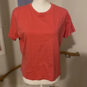 Röd t-shirt från H&M - Säljer en enkel och stilren rosa/röd t-shirt från H&M. Den har en klassisk rund hals och korta ärmar, perfekt för en avslappnad look. Tillverkad i ett mjukt och bekvämt material.