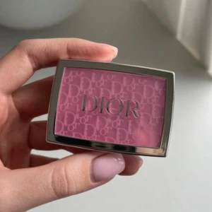 Dior Rosy Glow Rouge - Säljer en Dior Rosy Glow rouge i en härlig rosa nyans. Kompakt förpackning med spegel, perfekt för touch-ups under dagen. Den har en elegant design med Dior-loggan präglad på ytan.