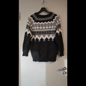 Svart och grå mönstrad stickad tröja - Säljer en snygg stickad tröja i svart och grått med ett geometriskt mönster. Tröjan har långa ärmar och en rund halsringning. Oversized. Hund finns i hemmet