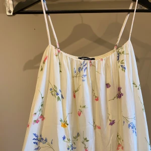 Blommig långklänning från Gina Tricot - Använd en gång.                                                   Fin långklänning från Gina Tricot med ett blommigt mönster i olika färger. Klänningen har smala axelband och en luftig passform🌸