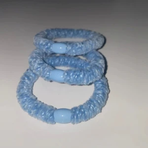  hårband kknekki - Tre stycken elastiska hårband i ljusblått med en slät plastdetalj. Perfekta för att hålla håret på plats med stil.
