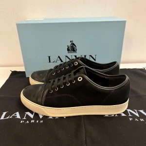 Svarta sneakers från Lanvin - Snygga svarta sneakers från Lanvin med vita sulor och klassisk snörning. Skorna har en stilren design med rund tå och är tillverkade i skinn. Perfekta för en stilren look. Pris kan diskuteras vid snabb affär 